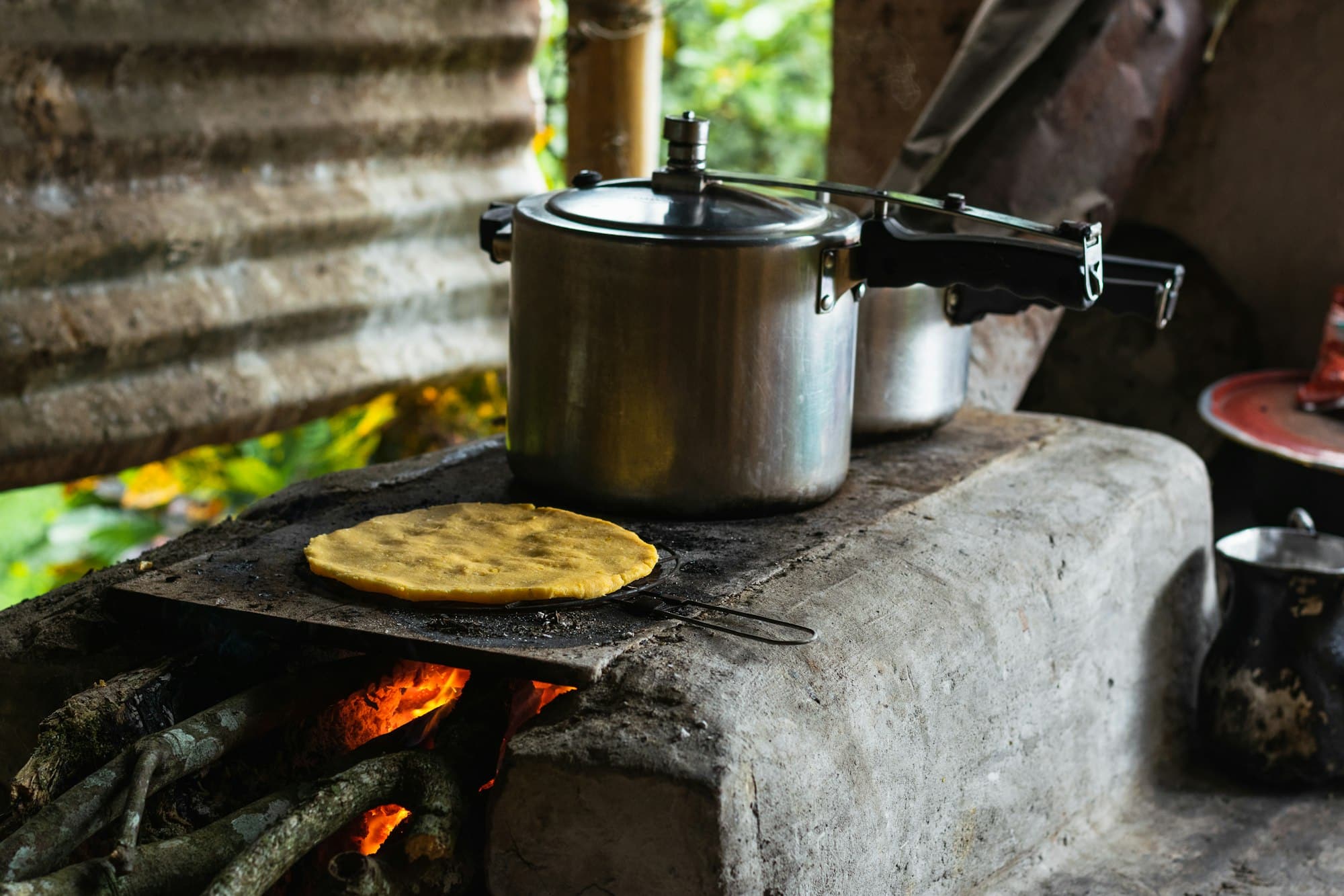 cooking on a Colombian farm, an arepa roasting next to a pressure cooker on a handmade brick stove